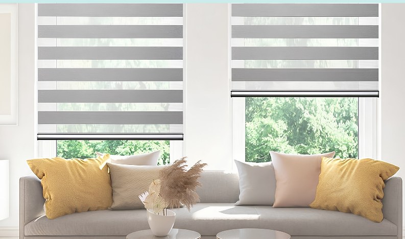 Two cordless zebra blinds over windows behind a sofa with yellow cushions