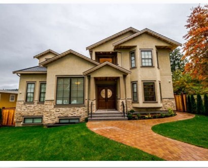 Stucco and stone family home with a brick paver driveway