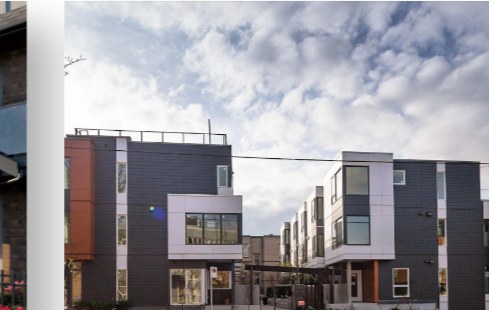 Modern grey multi-unit townhomes under a bright sky